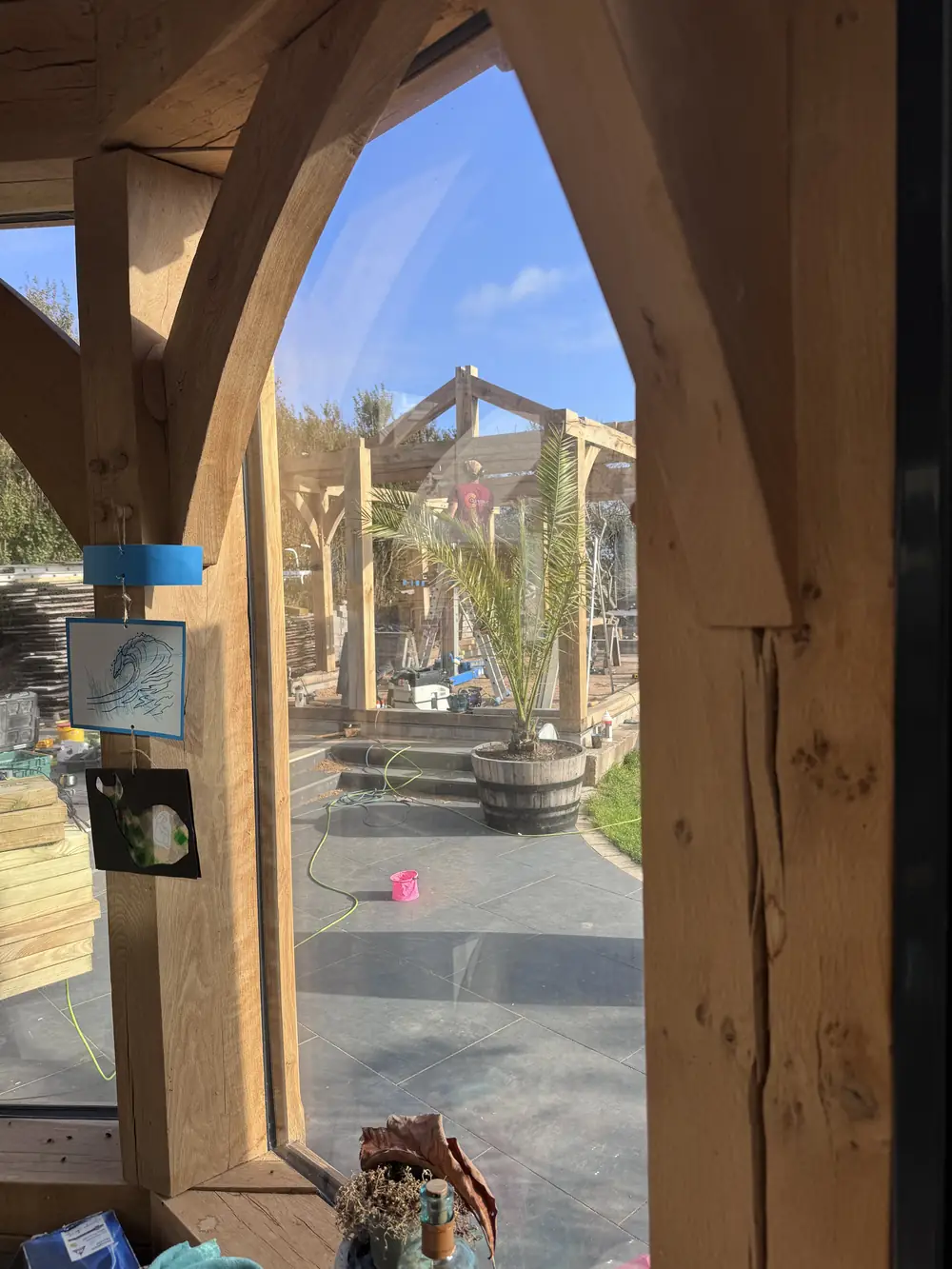 A Gothic-arched oak window opening in a green oak frame, looking out to the garden.