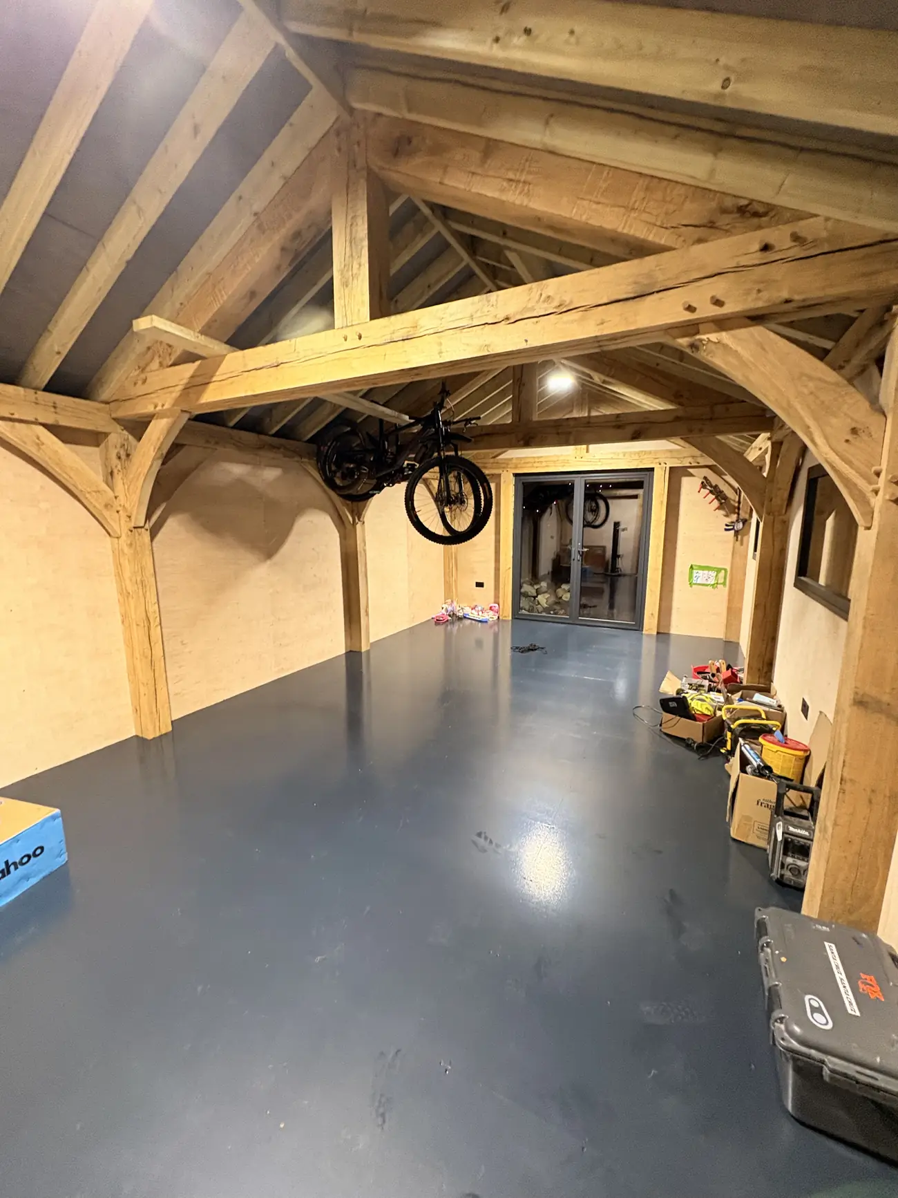The inside of a finished oak framed building, with the frame's trusses and braces left exposed overhead.